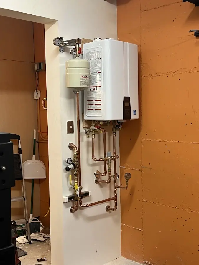 Plumbing technician inspecting water heater connections in North Greenbush